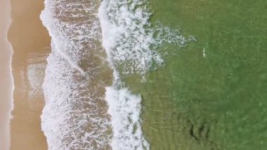 Drone kumlu sahilde dalgaları yakalar.