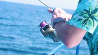 Tropikal gömlekli bir adam Phuket, Tayland 'da gün ışığında tekneden balık tutar.