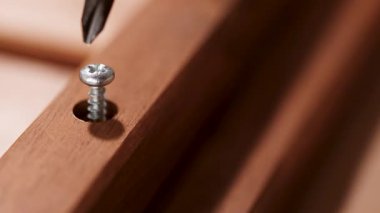 Tahtaya elektrikli matkapla vurulan vidanın yakın çekimi, hassasiyet ve işçiliği vurguluyor.