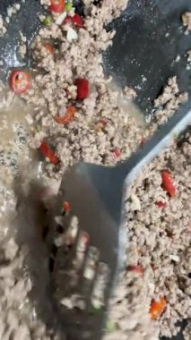 Kıymalı domuz eti, kırmızı biber ve sebzeyle kızartılır. Parlak mutfak ışıkları altında, spatulayı karıştırmak için kullanılır.