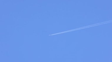 Uçak açık mavi gökyüzünde iz bırakıyor