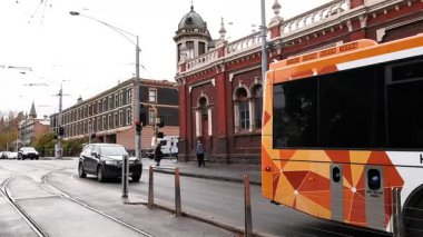 Otobüs ve araba tarihi kırmızı tuğla binayı geçiyor