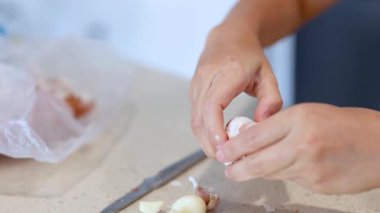 Mutfak tezgahında sarımsak soyan, yumuşak ışıklandırmalı ve odaklanmış kompozisyonu olan ellerin yakın çekimi.