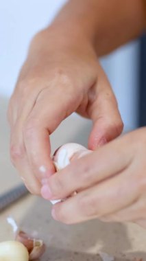 Mutfak tezgahında doğal ışıklandırmalı sarımsak karanfilleri soyan ellerin yakın çekimi.