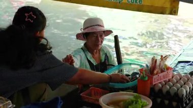 Satıcı, yüzen bir pazarda mal satıyor.