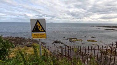 Crail 'de kayalık sahil kenarında uyarı işareti