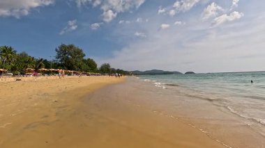 Phuket, Tayland 'da sakin bir sahil sahnesi. Yumuşak dalgalar ve sakin bir günbatımı atmosferi var.