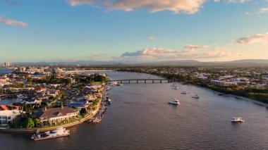 İnsansız hava aracı lüks malikaneleri ve sıcak günbatımı altında tekneleri olan sakin Altın Sahil su yollarını yakalıyor ve sakin bir kıyı atmosferini gösteriyor.