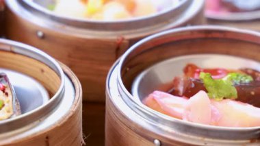 Bambu sepetlerinde renkli Dim Sum 'un yakın çekimi, restoranda doğal ışıklandırma altında canlı malzemeler sergileniyor.