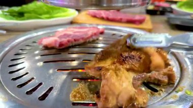 Bangkok 'taki Kore mangalında et ızgarası. Canlı renkler ve hareketli hareketler canlı bir yemek ortamında yakalanır.