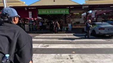 Yayalar Kraliçe Victoria Pazarı 'na giden yolu geçiyorlar.