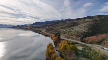 Dunstan Gölü 'nün çevresini çevreleyen hava manzarası, canlı sonbahar yaprakları ve dolambaçlı bir yol.