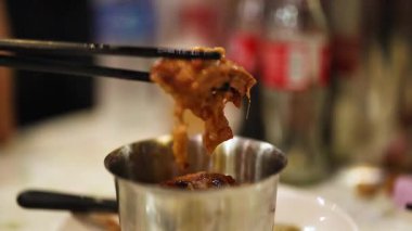 Çubuklar metal bir bardaktan domuz eti kaldırıyor.
