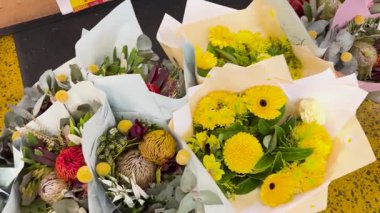 Parlak ışıklandırmalı, çiçekçi dükkanında çeşitli çiçek aranjmanları sergilenen tezgahın üzerinde canlı çiçek buketleri sergileniyor.