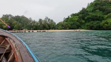 Uzun kuyruklu tekne yemyeşil adanın sahiline yaklaşıyor.