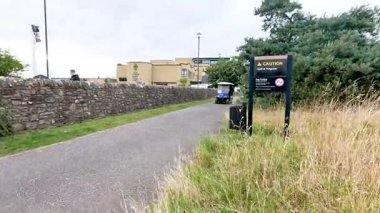 Golf arabası manzaralı yolda ilerliyor.