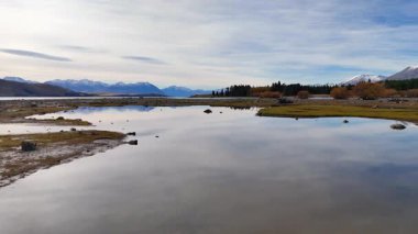 Hava görüntüleri Tekapo Gölü 'nün sakin manzarasını yansıtıcı sularla ve yumuşak gün ışığı altında sonbahar yapraklarıyla yakalar.