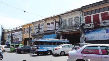 Güneşli bir günde eski binaların önünden trafik akıyor