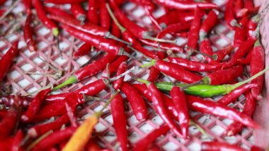 Örülmüş bir yüzey üzerinde dinamik kamera hareketi ve doğal ışıklandırmayla renklendirilmiş kırmızı biberlerin yakın çekim videosu.