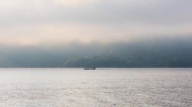 Bir tekne sisli bir göl yüzeyinde hareket eder.