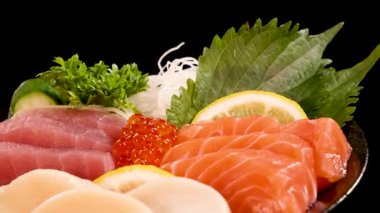 Canlı bir tabak somon, ton balığı, deniz tarağı ve somon yumurtası parlak stüdyo ışıkları altında pürüzsüzce döner, taze dokular ve renkli süslemeler renklendirir.