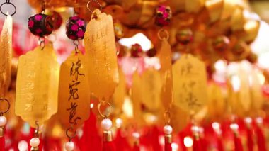 Tapınakta kırmızı püsküllü altın çanlar asılı.