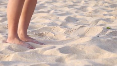 Person walking barefoot and kicking sand on Karon Beach, Phuket