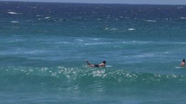 Okyanus dalgalarında yüzen ve oynayan insanlar