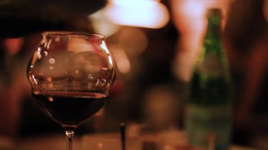 Kırmızı şarapla dolu bir şarap kadehi yumuşak, rahat bir ortamda rahatlama ve hoşgörü anı yakalar.