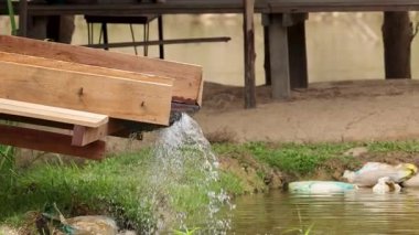 Bir ahşap kanallar su kanallarını çimenlerle çevrili bir göle ve kırsal bir çevreye doğal gün ışığı altında çevirir.