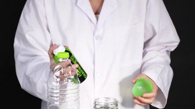 Laboratuvar önlüklü bir insan, laboratuvar ortamında tıraş köpüğü, su ve beher kullanarak kimyasal bir deney yapar.