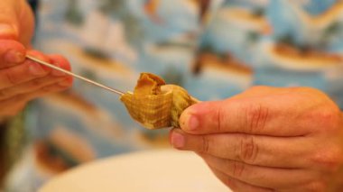 Bir aletle midyeyi kabuktan çıkaran kişi