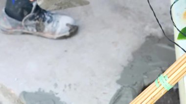 İşçi ustalıkla ıslak betonu bir inşaat sahasında malayla ıslatıyor. Yakın çekim hassasiyeti ve tekniği vurgular.