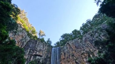 Şelale kayalık bir uçurumdan aşağı yuvarlanıyor.