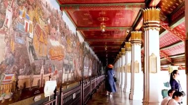 Ziyaretçi Bangkok tapınağındaki karmaşık duvar resimlerine hayran.