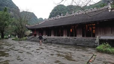 Geleneksel bir Vietnam binasının yanında yürüyen insanlar.