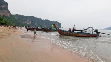 İnsanlar Krabi 'de sahilde ve teknelerde eğleniyor.