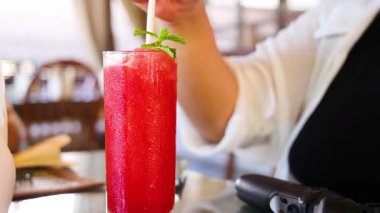 Konforlu bir Tayland kafesinde taze malzemeler ve gevşemiş bir atmosferi vurgulayan canlı bir karpuz suyu hazırlayan bir insan.