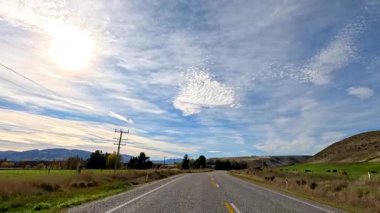 Queenstown, Yeni Zelanda 'da güneşli bir yolda sakin bir yolculuk. Sonbahar yapraklarını, açık gökyüzünü ve sakin kırsal manzarayı gözler önüne seriyor.