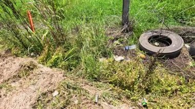 Yol kenarındaki çitlere saçılmış eski lastikler.