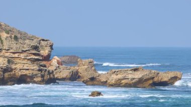 Dinamik okyanus dalgaları, Mornington Yarımadası 'ndaki berrak gökyüzünün altındaki engebeli kayalıklara çarpar ve gün ışığında yakalanır.