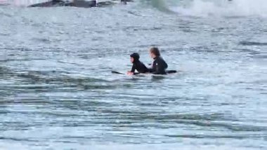 Hoca bir çocuğa sörf yapmayı öğretiyor.