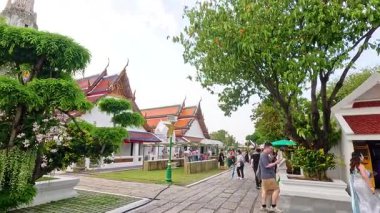 Ziyaretçiler Wat Arun, Bangkok 'ta gün ışığında dolaşarak tapınağın mimarisini ve yemyeşil alanını ele geçiriyorlar.