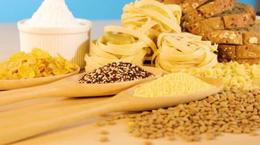 Tahıl ve makarna çeşitleri parlak ışık altında ahşap bir yüzey üzerinde düzenlenir, canlı ve davetkar bir sahne yaratır.