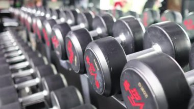 İyi aydınlatılmış bir spor salonunda halterler, dinamik kamera açısıyla spor ve dayanıklılık eğitimini vurguluyorlar.