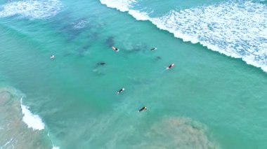 Okyanus Korusu, Avustralya 'da turkuaz dalgalarda sörf yapan sörfçüleri görüntüler. Parlak gün ışığı canlı okyanus manzarasını güçlendirir.