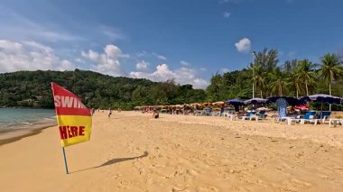 Phuket, Tayland 'da canlı bir plaj sahnesi,' Burada Yüzün 'bayrağı, açık gökyüzü, ve nazik dalgalar