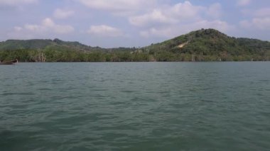 Sakin su ve mavi gökyüzünün altındaki yeşil tepeler