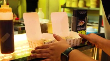 Ahırda bir kutu kızarmış çörek açan kişi.