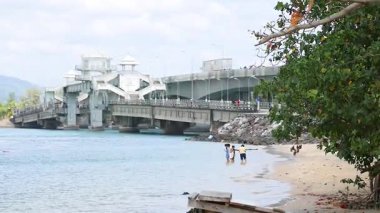 Sarasin Köprüsü, Phuket 'te, güneşli bir günün tadını çıkaran insanların olduğu sakin bir sahne.